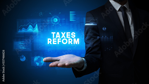 Hand of Businessman holding TAXES REFORM inscription, business success concept