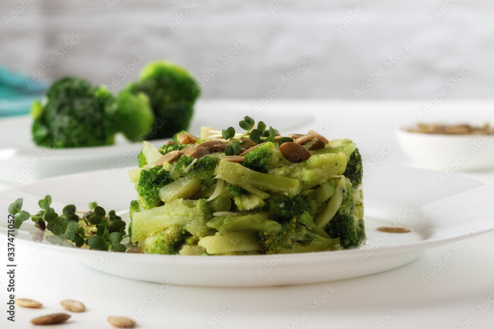 Boiled broccoli with pumpkin seeds on a white plate on the table Boiled broccoli with pumpkin seeds on a white plate on the table