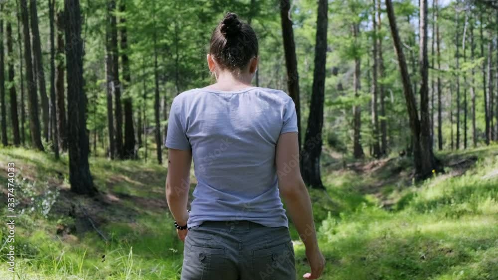 Girl walking in the green forest in sunny day. Back view, slow motion, 4K Girl walking in the green forest in sunny day. Back view, slow motion, 4K