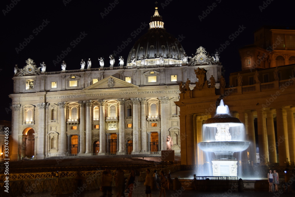 Night view of the illuminated fountains in St. Peter's Square with the basilica in the background. Travel concept