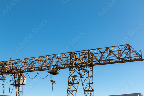 Vintage working gantry crane rusty yellow, bottom view, close-up against a blue spring sky © светлана аксенова