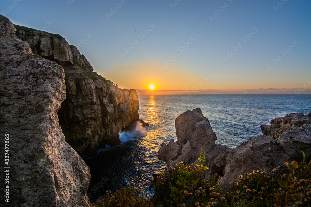 Amazing sunset in the north of Spain, Cantabria. Cliff with a lot of rocks and clear sky with the sea calm down. 