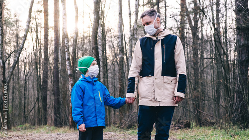 an adult and a child walk in the park during quarantine in medical masks, protection against infection