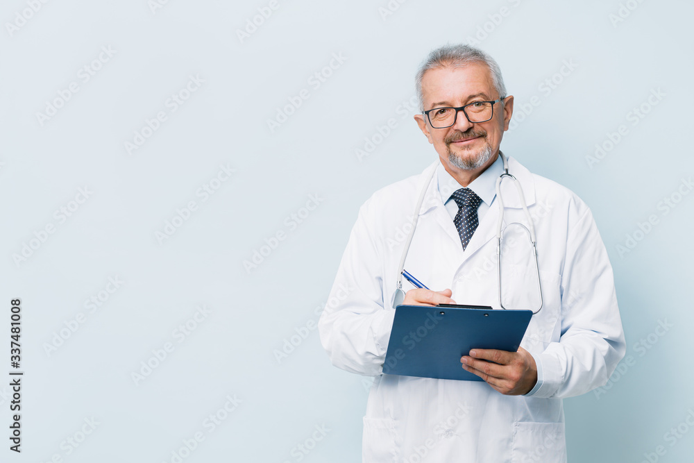 Elderly bearded male doctor in white uniform with a stethoscope with a blue folder. Doctor on the background of a medical research laboratory. Elderly bearded male doctor in white uniform with a stethoscope with a blue folder. Doctor on the background of a medical research laboratory.