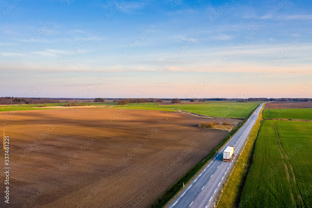 Aerial view of a highway passing through spring agricultural fields at sunset