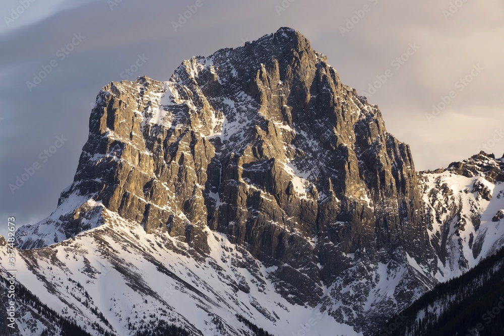Snowy Little Sister Mountain Peak Lit by Sunlight with Dark Sky Background.  Canmore, Alberta Canadian Rocky Mountains