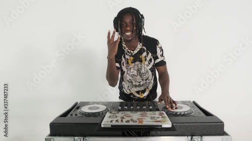 Young stylish black guy man dj posing behind mixing console on white studio background