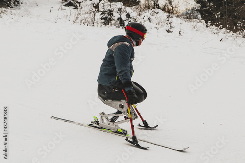 Athlete with disabled or missing limbs racing in a mono ski event for paralyzed people. Invalid on a ski slope, competing. photo