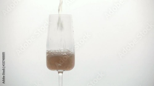 pours champagne slowly into a glass