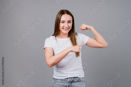strong woman showing biceps isolated on grey background