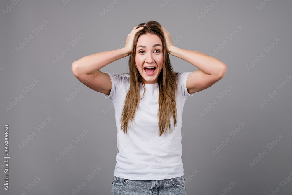 woman holding head smiling and screaming isolated on grey background woman holding head smiling and screaming isolated on grey background