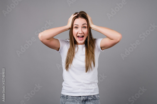 woman holding head smiling and screaming isolated on grey background