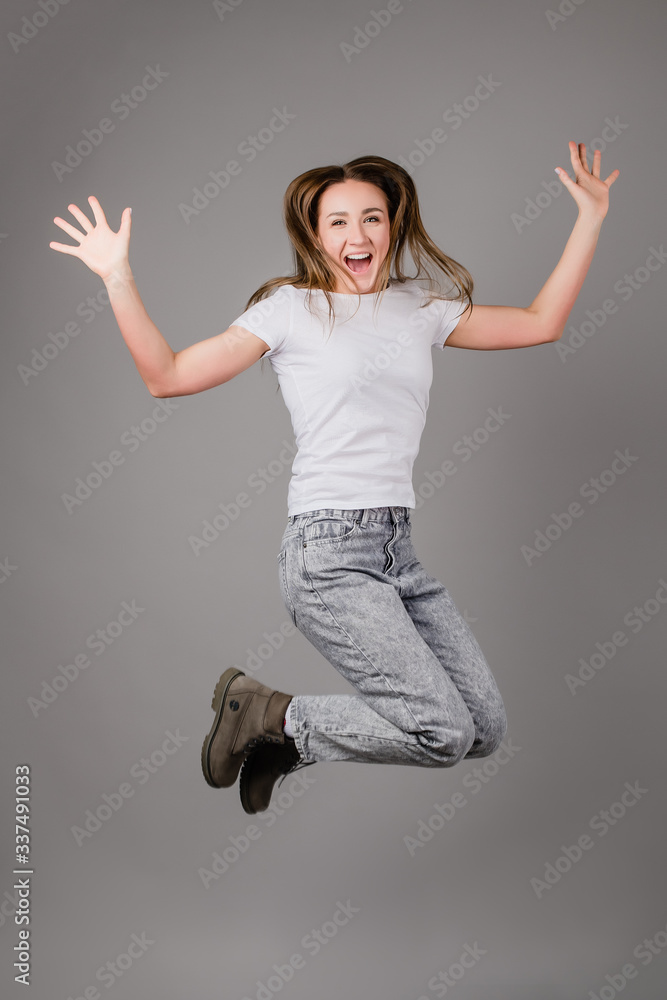 happy woman jumping high in air and screaming isolated on grey background