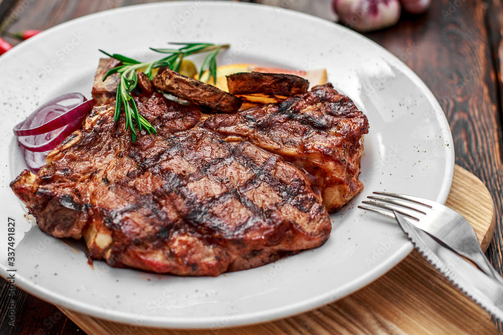 A large steak with spices and vegetables on the grill A large steak with spices and vegetables on the grill