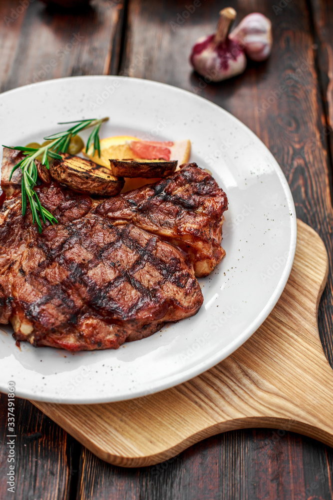 A large steak with spices and vegetables on the grill