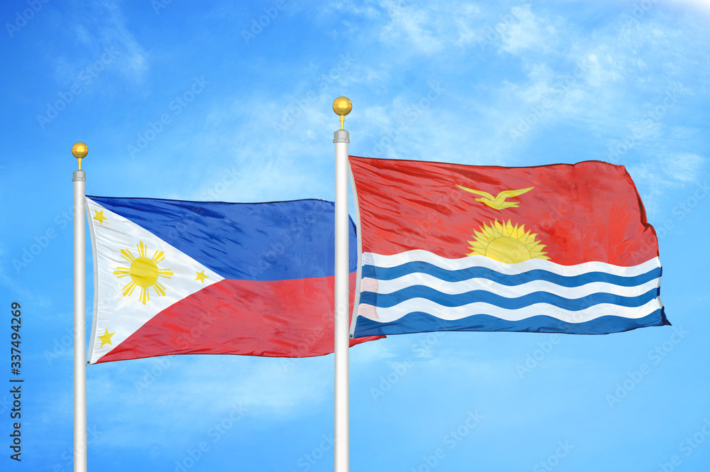 Philippines and Kiribati two flags on flagpoles and blue cloudy sky Philippines and Kiribati two flags on flagpoles and blue cloudy sky