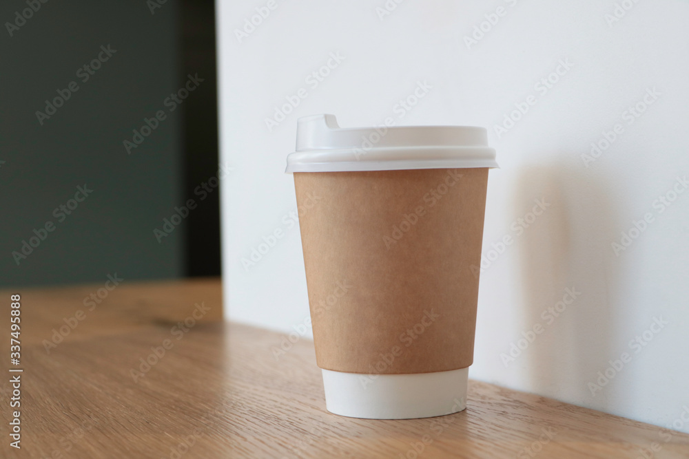Mock up with a cup of coffee. A glass is on the table in a cafe, selling coffee in the background. Coffee to go. Light walls. Wooden table. Cafe. Disposable cup Mock up with a cup of coffee. A glass is on the table in a cafe, selling coffee in the background. Coffee to go. Light walls. Wooden table. Cafe. Disposable cup