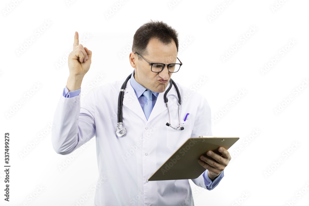 Disgruntled male doctor in white coat and stethoscope holds thumb up looking on clipboard with patient's diagnosis on isolated white background. Copy space. Healthcare, diseases, medical concept Disgruntled male doctor in white coat and stethoscope holds thumb up looking on clipboard with patient's diagnosis on isolated white background. Copy space. Healthcare, diseases, medical concept
