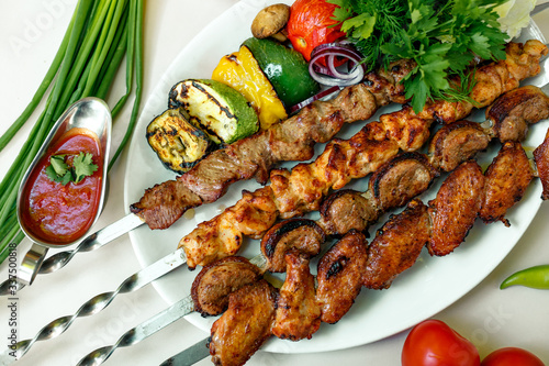 assorted of kebabs with grilled vegetables, pickled onions, herbs and spicy sauce