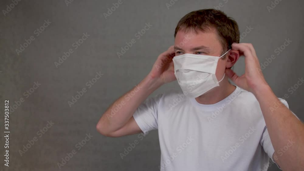 Man measures body temperature looks at a thermometer and puts a mask on his face Man measures body temperature looks at a thermometer and puts a mask on his face