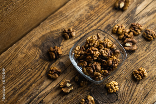 Walnut in a smale plate with scattered shelled nuts which standing on a wooden vintage table. Walnuts is a healthy vegetarian protein nutritious food. Walnut on rustic old wood.