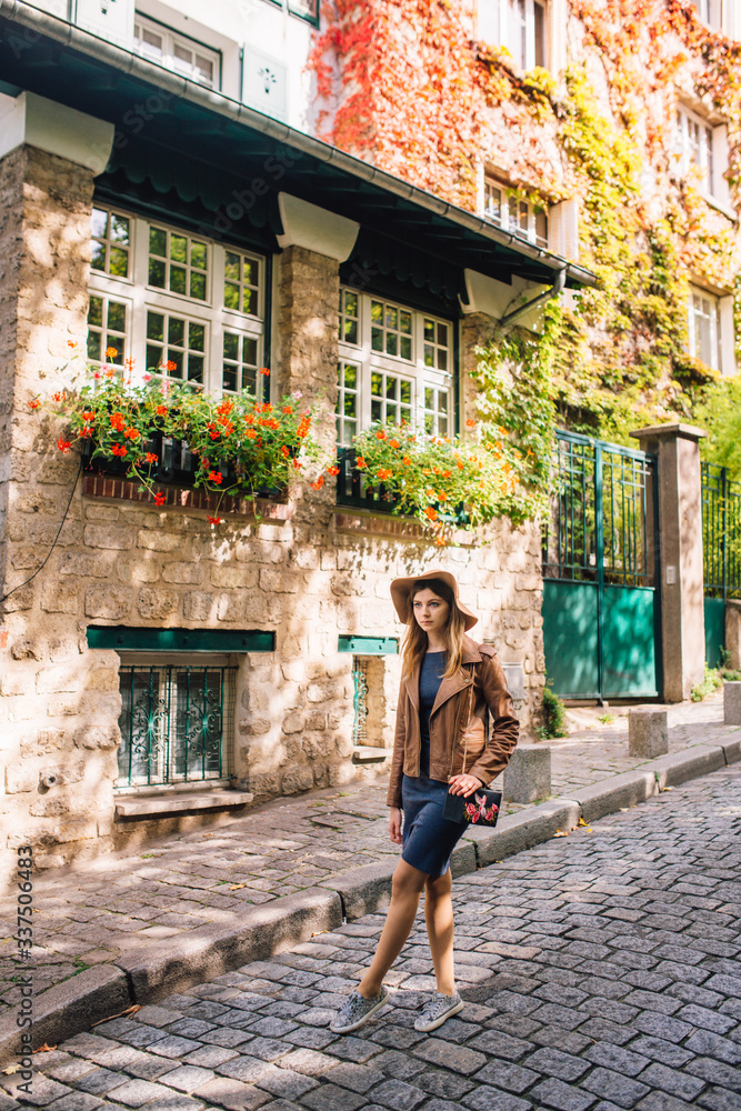 A beautiful young woman in a brown jacket walks in the early morning on the famous Montmartre hill in Paris A beautiful young woman in a brown jacket walks in the early morning on the famous Montmartre hill in Paris