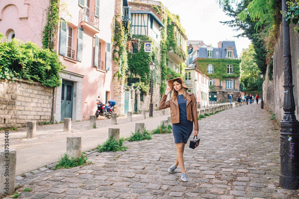 A beautiful young woman in a brown jacket walks in the early morning on the famous Montmartre hill in Paris