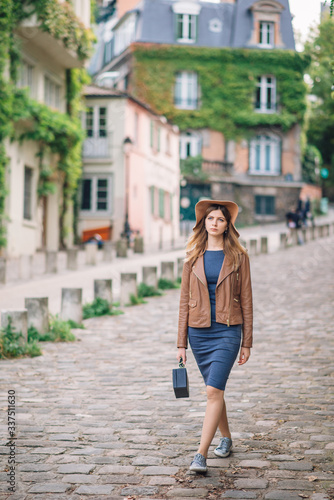 A beautiful young woman in a brown jacket walks in the early morning on the famous Montmartre hill in Paris