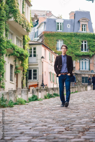 a man in a jacket and jeans walks in Montmartre, Paris