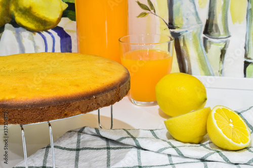 Moroccan meskouta cake with orange juice and lemon and paintings in the background, fresh bakery of oven, yummy dessert, tasty looking, recipe guide, culinary book, yellow snack, birthday celebration photo