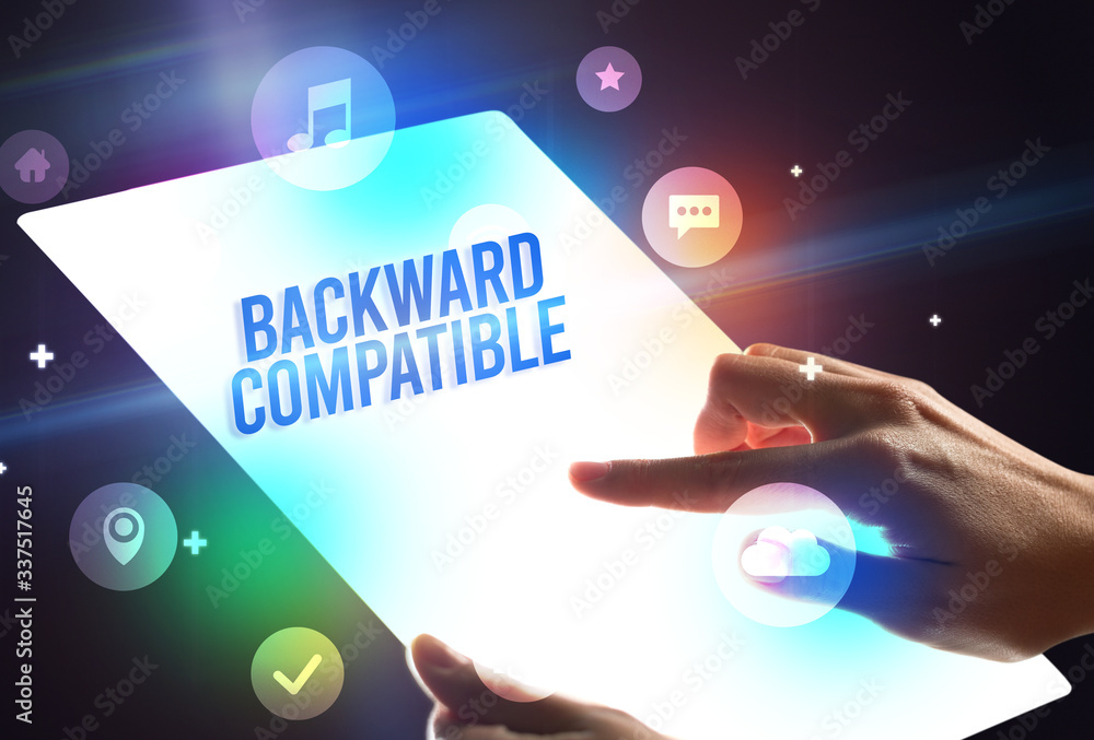 Holding futuristic tablet with BACKWARD COMPATIBLE inscription, new technology concept Holding futuristic tablet with BACKWARD COMPATIBLE inscription, new technology concept