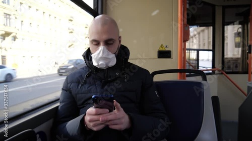 A middle-aged man infected with a coronavirus rides a bus sitting at a window in a deserted city and types a message on his phone