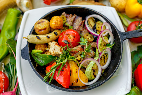 fried meat on the frying pan with vegetables and baked potatoes with vegetables