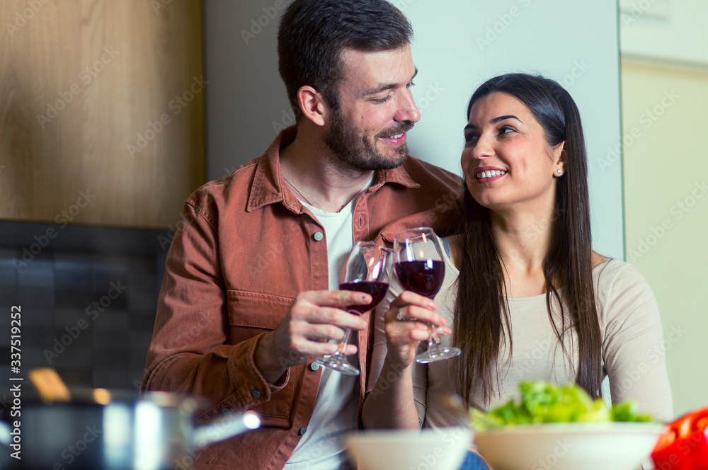 Cute couple drinking wine in the kitchen while preparing dinner Cute couple drinking wine in the kitchen while preparing dinner