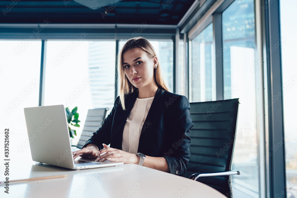 © BullRun - Portrait of blonde female manager sitting at working table with laptop computer typing and sending business emails,confident intelligent formally dressed woman looking at camera during working process © BullRun - Portrait of blonde female manager sitting at working table with laptop computer typing and sending business emails,confident intelligent formally dressed woman looking at camera during working process