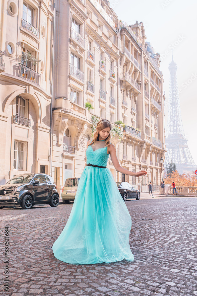 Beautiful young girl in a dress on the street with a view of the Eiffel tower