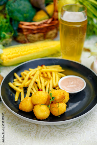 Cheese balls with crispy fresh French fries with sauce on a decorated table