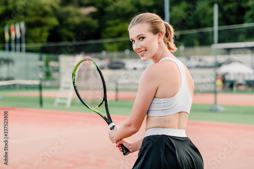 Vászonkép smiling tennis player looking over shoulder on court with racket