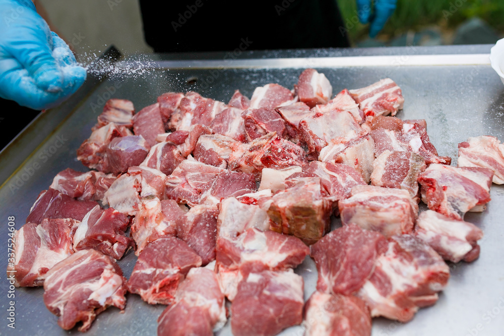 Close-up. Man cook sprinkles with salt chopped into small pieces red meat for frying barbecue