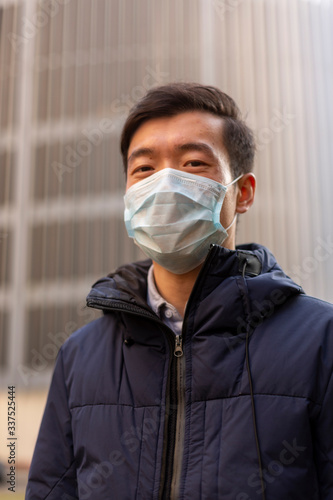 Beautiful asian young man. Chinese guy in facial mask against 2019-nCov. Outside. Prevent spread of corona virus. China closing country concept. Chinese coronavirus outbreak.