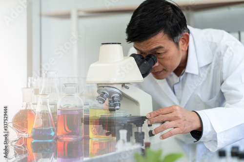 Scientist using microscope in laboratory with test tube background. Medical healthcare technology and pharmaceutical research and development concept