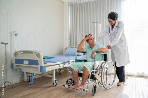 The african american doctor is pushing the wheelchair And provide consultation regarding treatment to patients sitting in a wheelchair and closely monitor