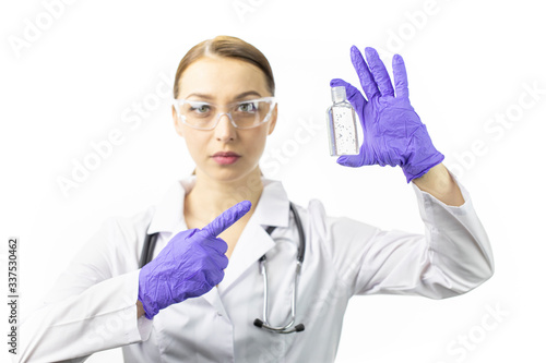 Beautiful female doctor in medical uniform pointing on sanitizer gel dispenser to prevent spread of germs  bacteria and virus. Focus on antiseptic. Quarantine  care  covid-19 protection concept
