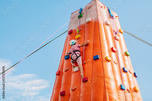 Boy practicing climbing on an inflatable climbing wall. Is behind