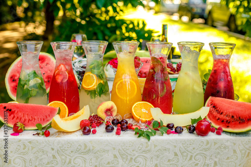fresh lemonade collection (watermelon, orange, lemon, strawberry and berry) in the street, on a wooden table with fruit