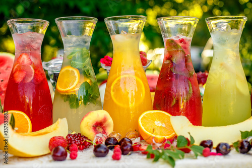 fresh lemonade collection (watermelon, orange, lemon, strawberry and berry) in the street, on a wooden table with fruit