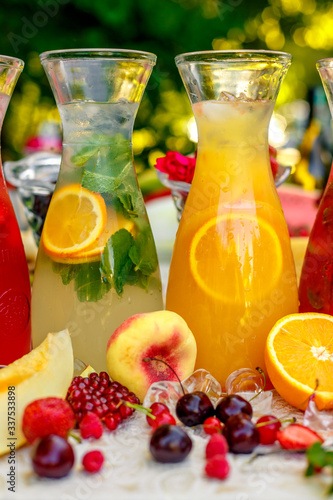 fresh lemonade collection (watermelon, orange, lemon, strawberry and berry) in the street, on a wooden table with fruit