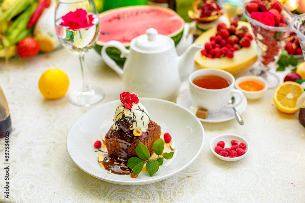 chocolate sponge cake with ice cream and fruit on a served table