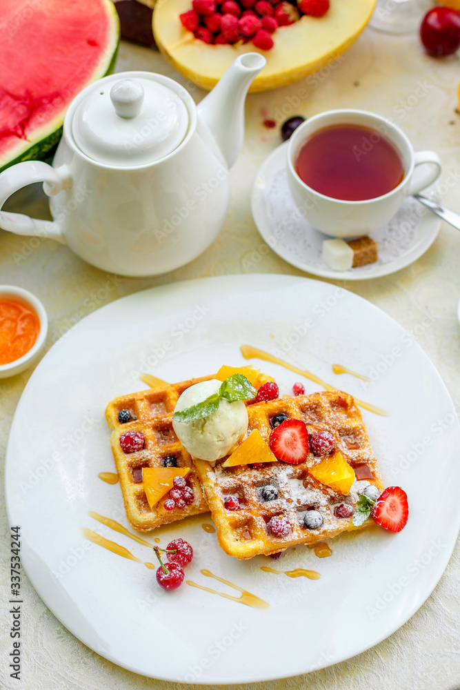 Belgian waffles with ice cream and fruits and berries on a white plate Belgian waffles with ice cream and fruits and berries on a white plate
