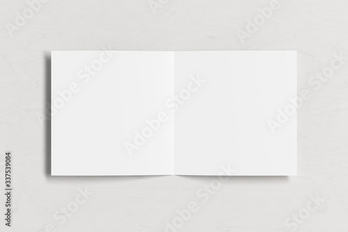 Blank square pages leaflet on white wooden background. Bi-fold or half-fold opened brochure isolated with clipping path. View directly above. 3d illustration © dimamoroz